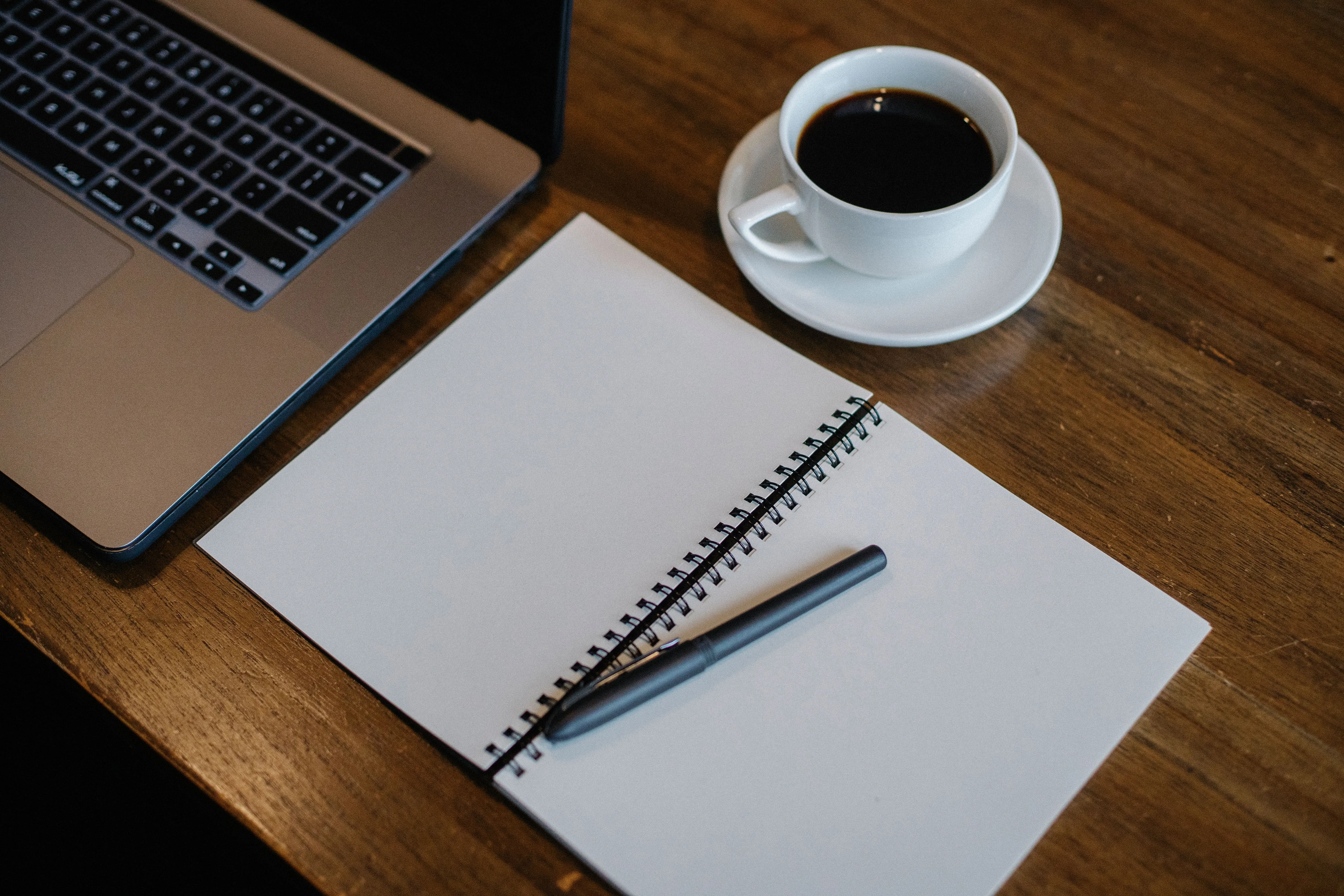 A warm, tidy office desk with a notebook, desk organizer and filing folders beside a window.